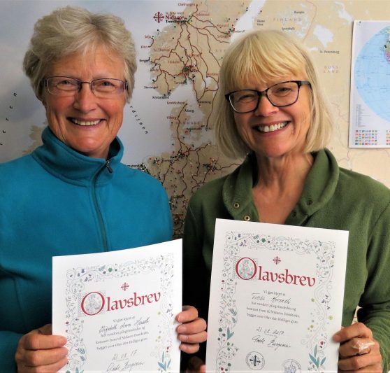 Two women holding up their Olav letters. Photo