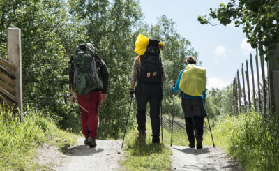 Three people with backpacks walking along a trail. Photo